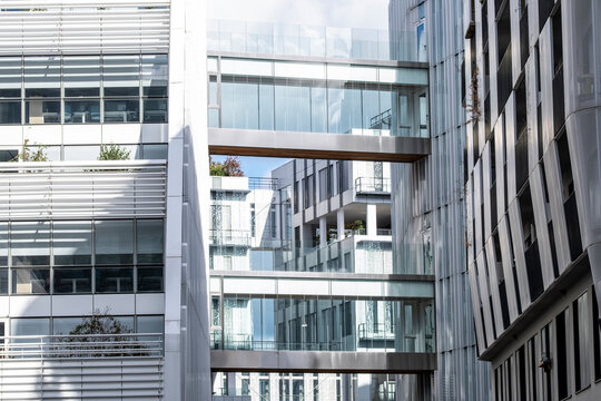 Glass walkways connect apartment buildings in Paris, where residential windows, balconies, facade reflections and urban architecture layer the courtyard