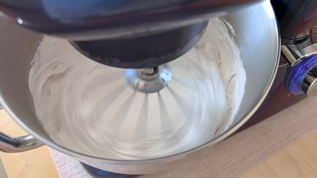 Stand mixer beating white marshmallow cream in metal bowl making zephyr dessert