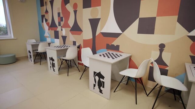 Rows of furniture set up with chessboard patterns and horse emblems on bases. Geometric mural creates stimulating learning environment