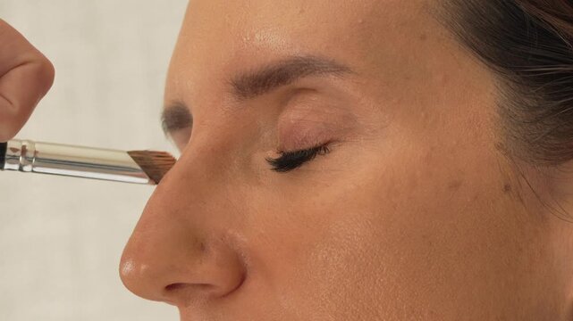 Makeup application woman, professional applies natural eyeshadow on eyelid and brow bone, close-up beauty routine