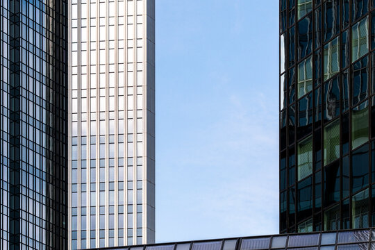 Between towers in Frankfurt Bankenviertel, Germany, a clear sky opens above glass office blocks, where urban architecture and facade lines shape depth