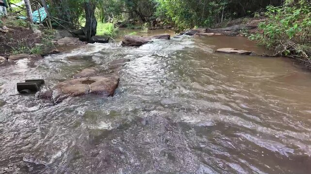 V&iacute;deo de queda d'&aacute;gua natural correndo sobre pedras escuras cercada por vegeta&ccedil;&atilde;o densa de floresta tropical no Parque Nacional da Chapada Diamantina, Bahia, Brasil.
