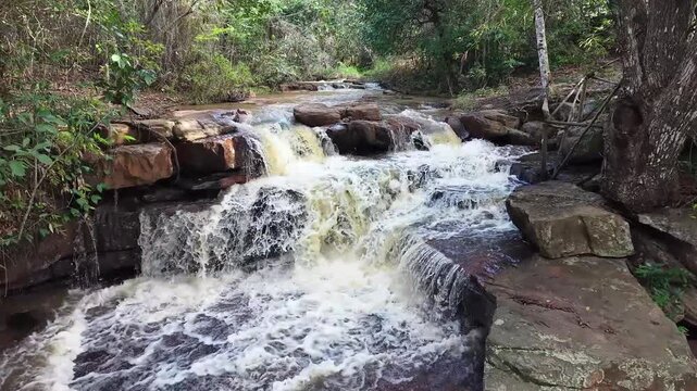 V&iacute;deo de queda d'&aacute;gua natural correndo sobre pedras escuras cercada por vegeta&ccedil;&atilde;o densa de floresta tropical no Parque Nacional da Chapada Diamantina, Bahia, Brasil.