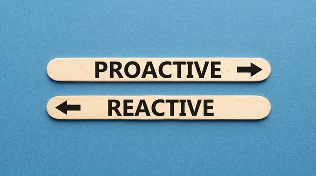 Wooden sticks printed with proactive and reactive lie on a blue background with arrows pointing in opposite directions, creating a simple visual comparison of contrasting approaches.
