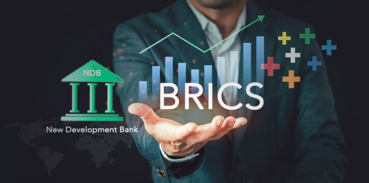 Businessman holding virtual interface showing BRICS economic alliance and New Development Bank NDB. Concept of global economic governance reform, local currency trade, and global south power.