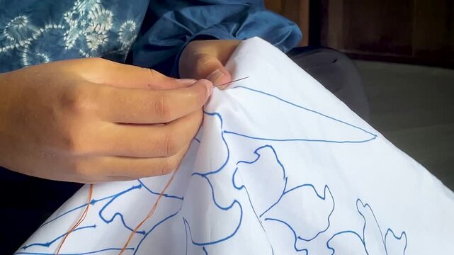 Artisan Hands Stitching Floral Pattern on White Fabric 
for Traditional Tie Dye Textile in Indonesia Workshop