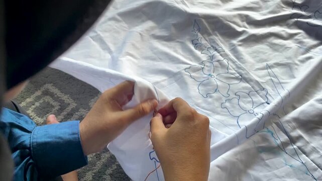 Artisan Hands Stitching Floral Pattern on White Fabric 
for Traditional Tie Dye Textile in Indonesia Workshop