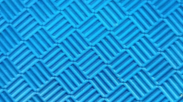 Close-up shot of a textured blue rubber mat with a grid pattern. Abstract background with geometric lines and non-slip surface texture, ideal for industrial, flooring, or design concepts.