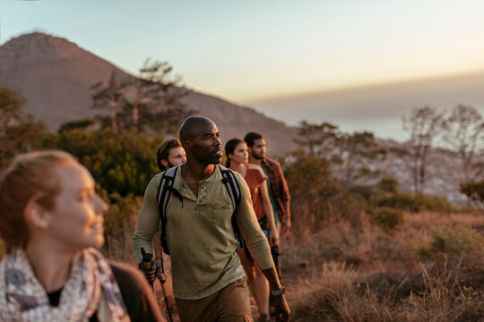 Friends hiking on a mountain trail at sunset