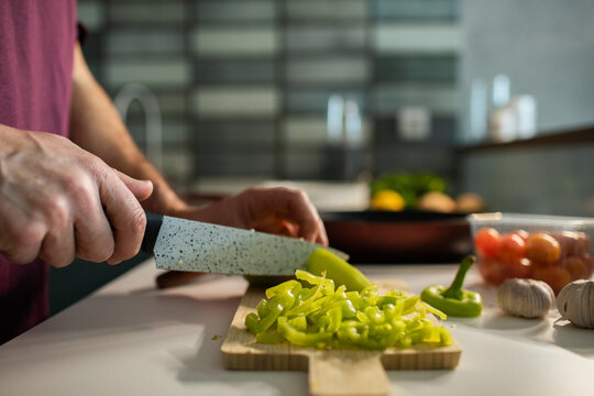 Person slicing green bell pepper in home kitchen