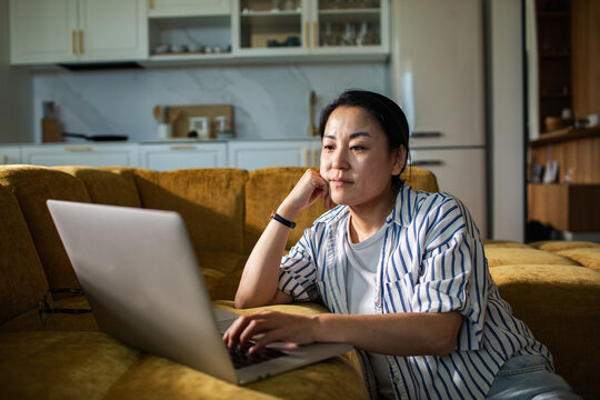 Focused woman using laptop on sofa at home