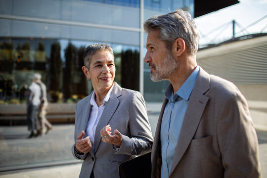 Senior business colleagues talking outside modern office building