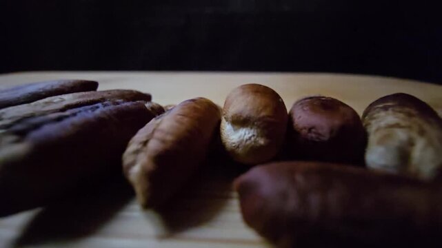 Close-up of dried date pits (seeds) arranged on a wooden board, highlighting the natural textures of palm seeds against a dark background, perfect for organic, agricultural, and culinary concepts.