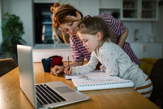 Mother helping daughter with homework at kitchen table