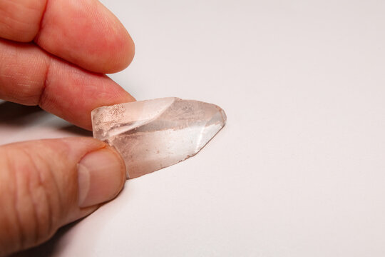 Natural stone, a piece of smoky quartz, held by a man; on white background with copyspace