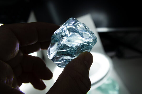 Crystal of glass in hand; on blurry background at a scientific research laboratory
