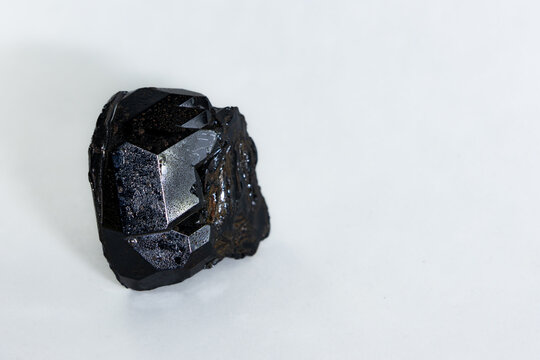 Closeup shiny black spinel or tourmaline crystal isolated on white background