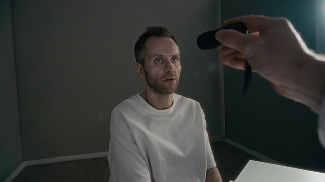 Medium shot of middle aged Caucasian man sitting in clinic while doctor conducts neurological eye exam with flashlight. Ideal for mental health awareness campaigns and psychiatric services advertising