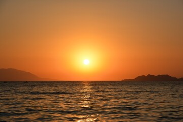 Fototapeta premium ​Golden sunset over the sea in Loutraki with Peloponnese mountains silhouette on the horizon