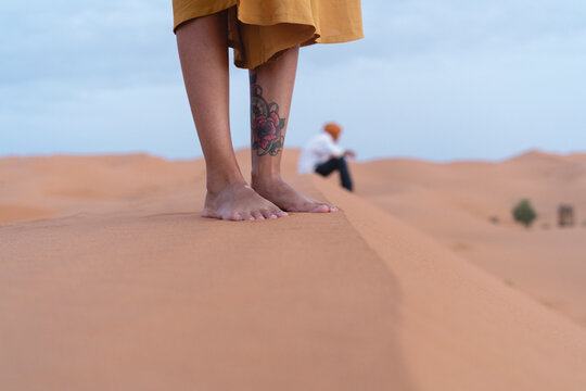 Feet of a woman standing on sand dune in Sahara Desert, Merzouga, Morocco