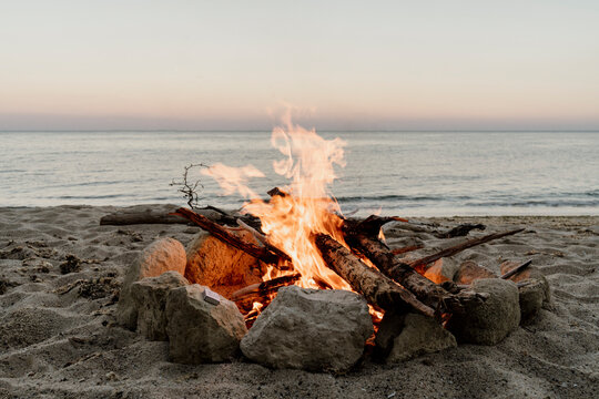 Campfire on empty beach during sunset