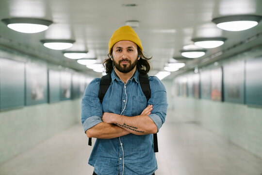 Portrait of bearded man with backpack and earphones in an underpass, Berlin, Germany