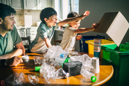 Family sorting plastic and cardboard waste for recycling at home