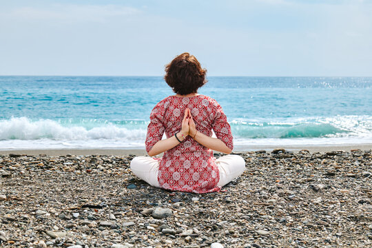 Person practicing yoga on a pebble beach by the Mediterranean sea