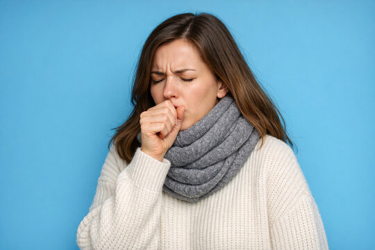 A woman covering her nose with her hand as she sneezes.