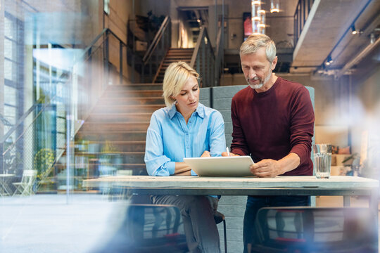 Business professionals planning on tablet in modern office setting