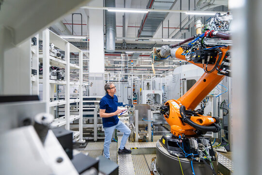Engineer operating industrial robot in automated manufacturing facility