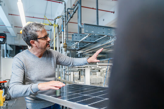 Engineer explaining photovoltaic system in production hall