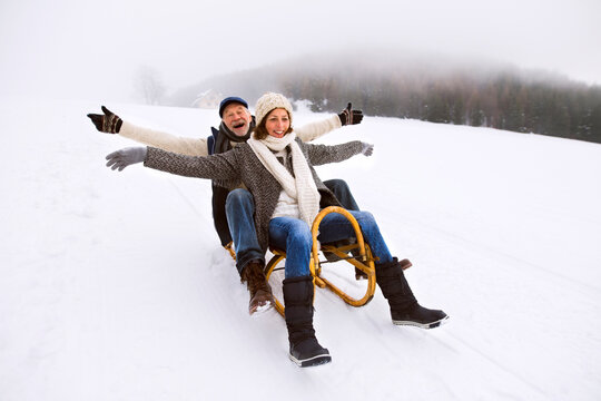 Senior couple having fun with sledge walking in the snow
