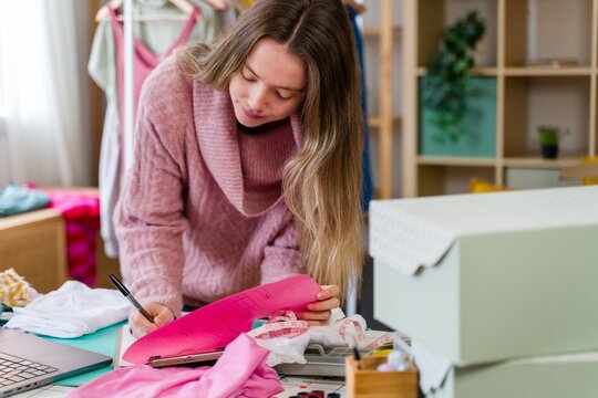 Fashion entrepreneur writing on clipboard at studio desk