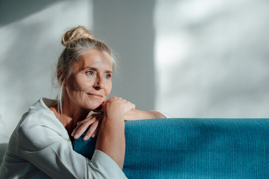 Thoughtful woman leaning on sofa at home