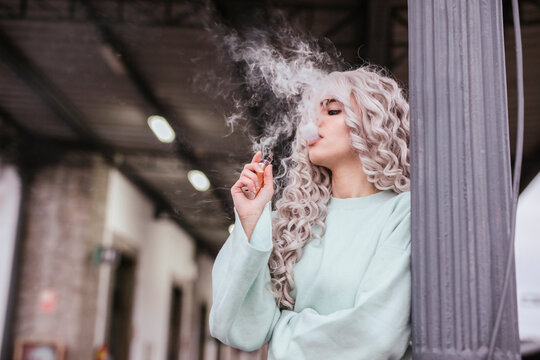 Young woman smoking electronic cigarette on platform