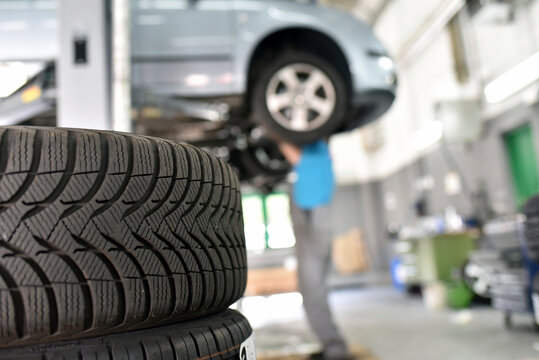 Car mechanic in a workshop, car tires in the foreground