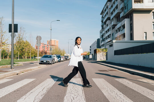 Smiling woman crossing street on sunny day