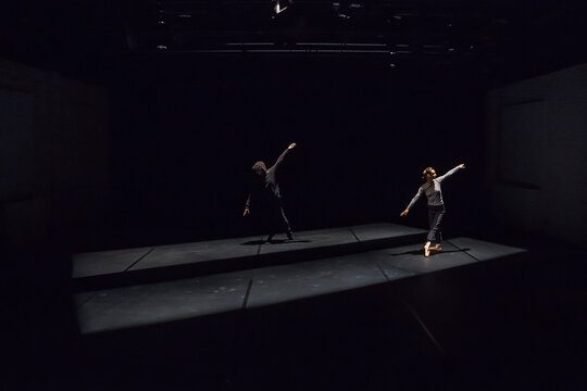 Male and female dancer performing comtemporary ballet on black stage