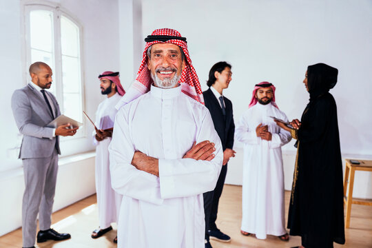 Saudi business leader smiling with diverse corporate team in office