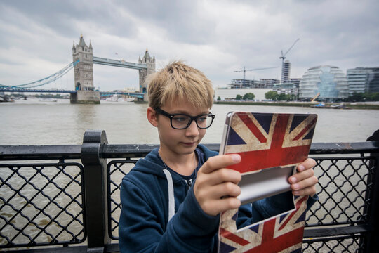 UK, London, boy taking picture with digital tablet at Tower Bridge