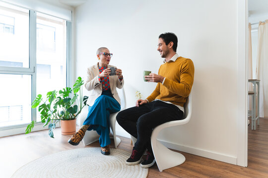 Colleagues talk and smile during a coffee break in the office