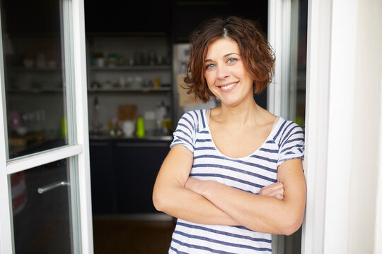 Portrait of content mature woman leaning against open balcony door