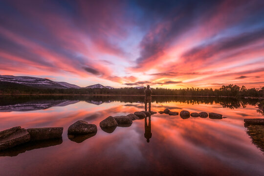 United Kingdom, Scotland, Highlands, Cairngorms National Park, Loch Morlich, sunset, hiker standing on stone