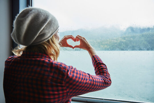 Chile, Hornopiren, woman shaping a heart with her hands at the window of a ferry