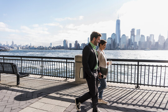USA, man and woman walking at New Jersey waterfront with view to Manhattan