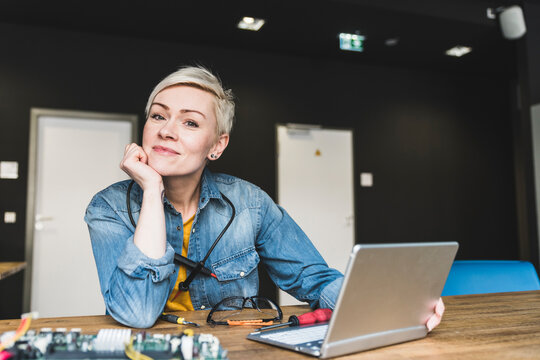 Portrait of smiling woman with laptop and computer equipment