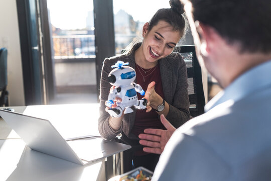 Colleagues smiling and discussing a toy robot in the office