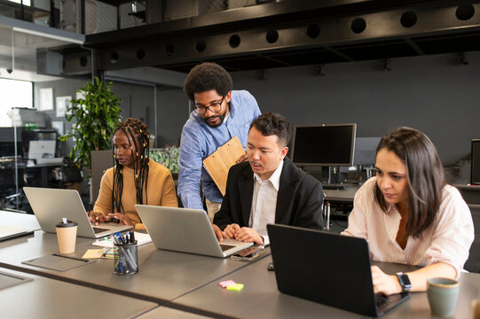 Young businessman discussing and planning with colleagues over laptop at desk
