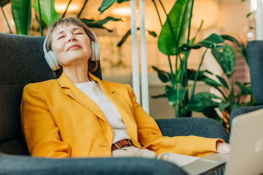 Businesswoman relaxing with headphones and laptop in modern office